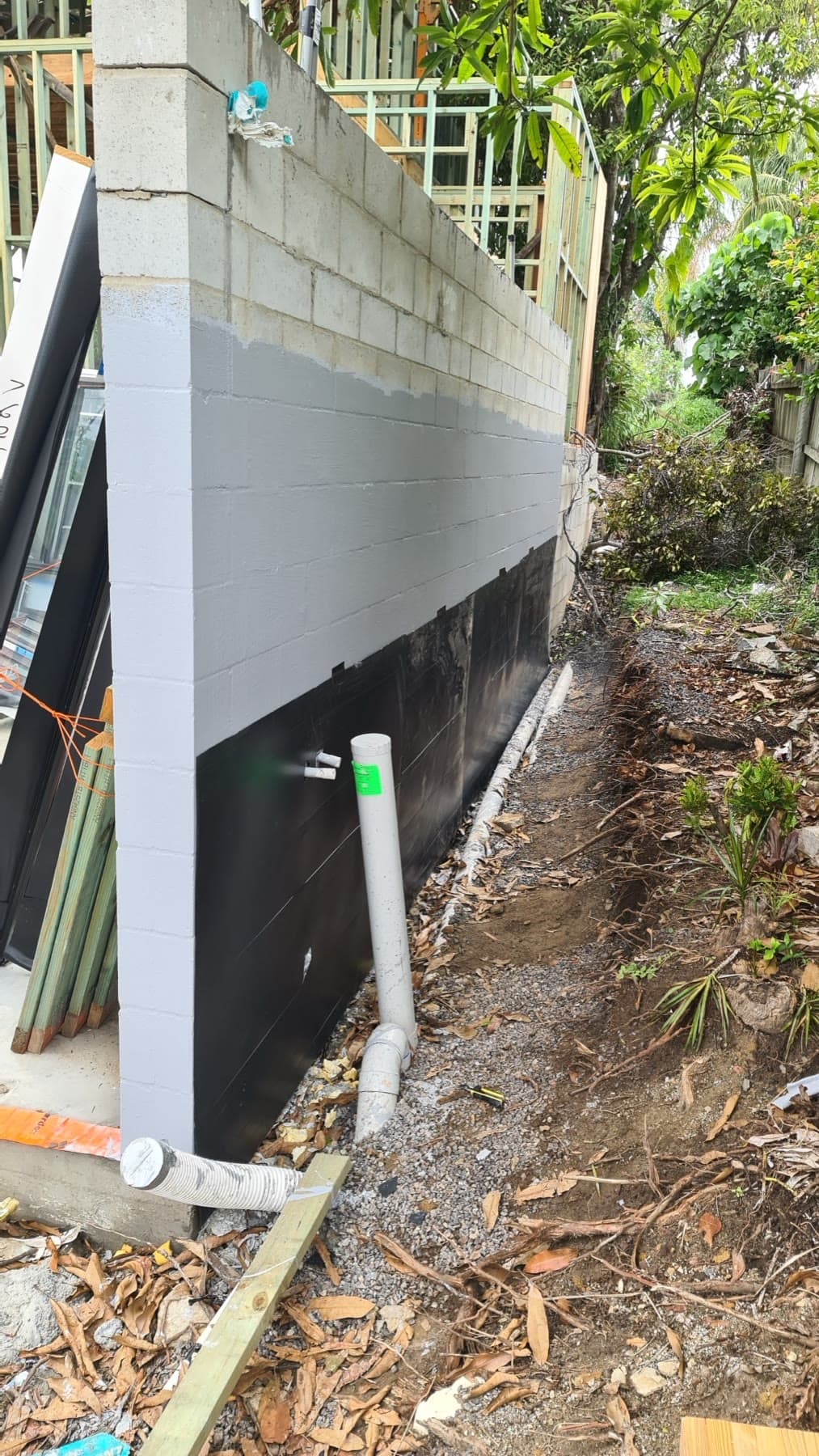 Exterior block wall with black membrane and drainage pipes