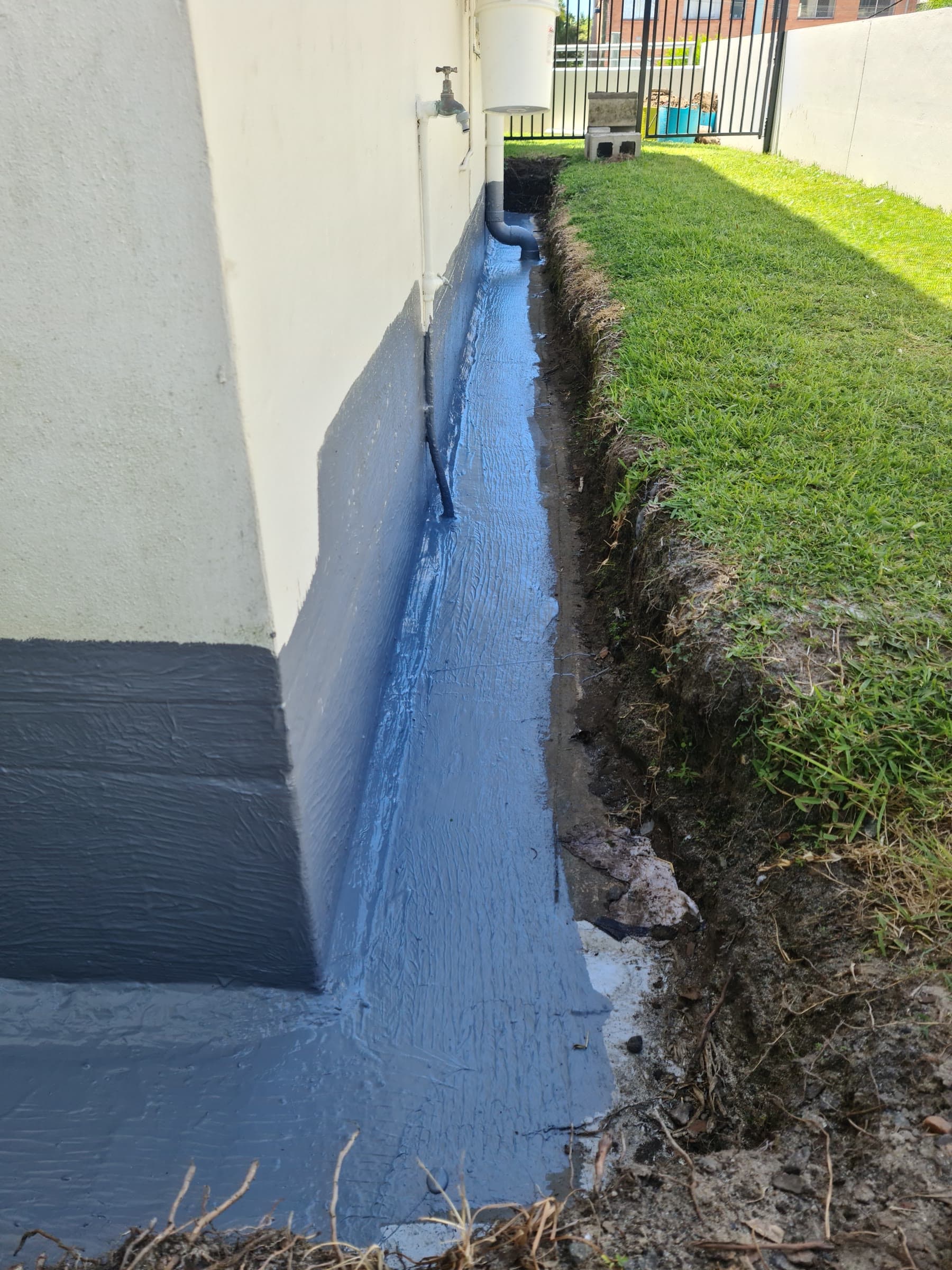 Foundation trench waterproofed with blue-grey liquid membrane