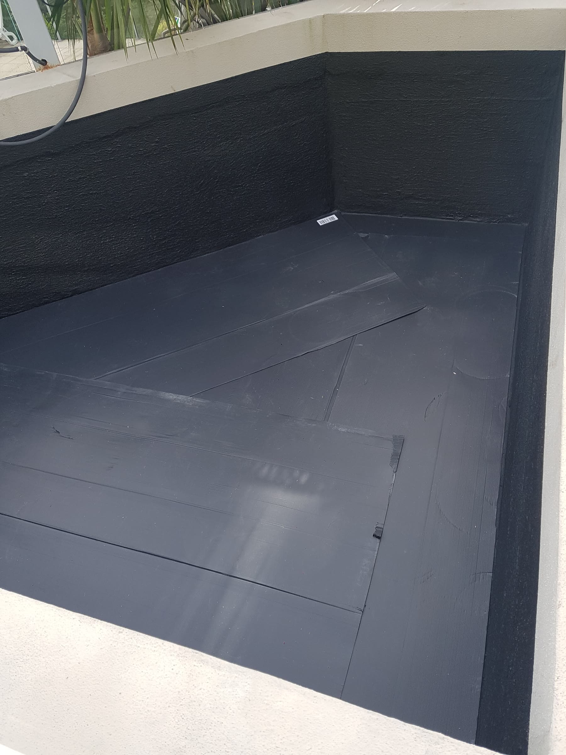 Planter box waterproofing with black membrane beside outdoor living space