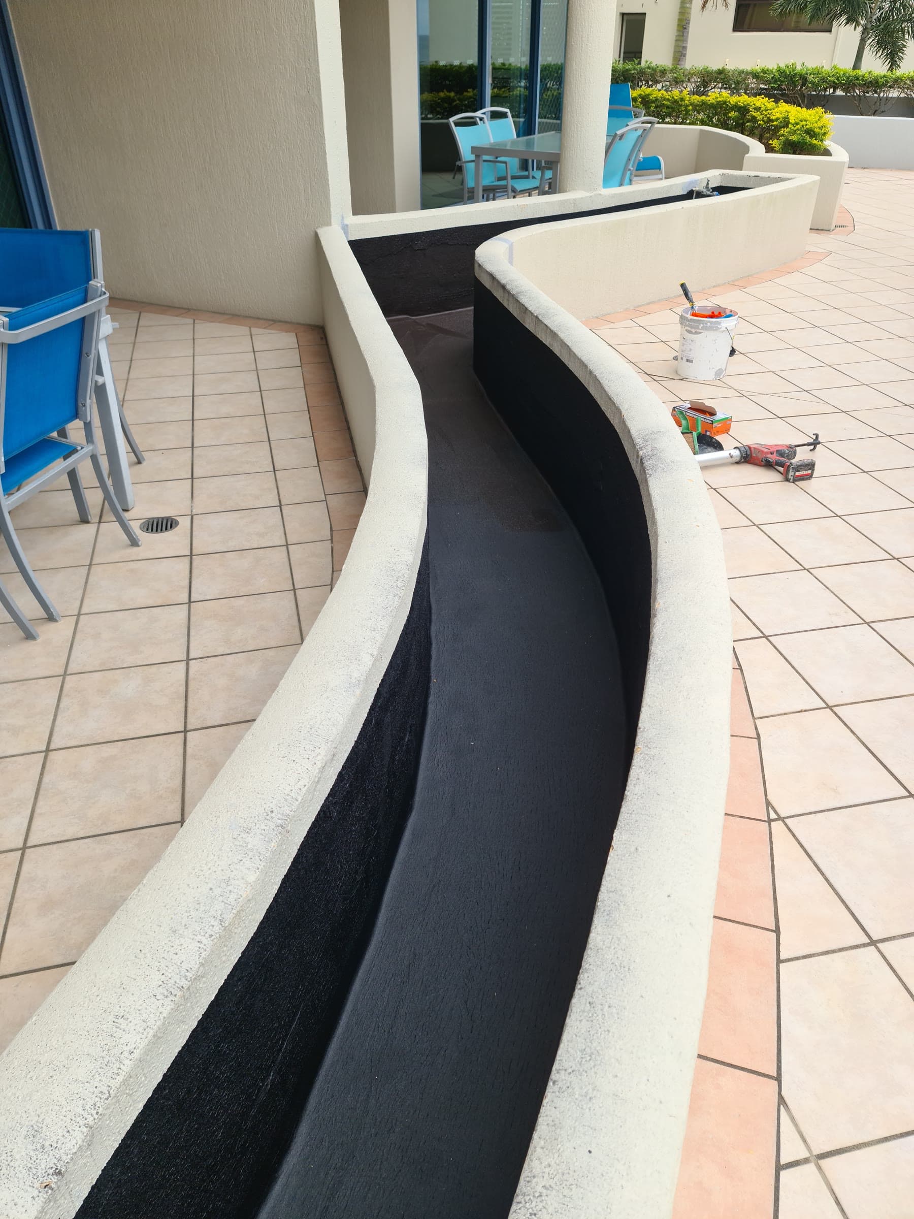 Curved terrace planter lined with black waterproofing membrane