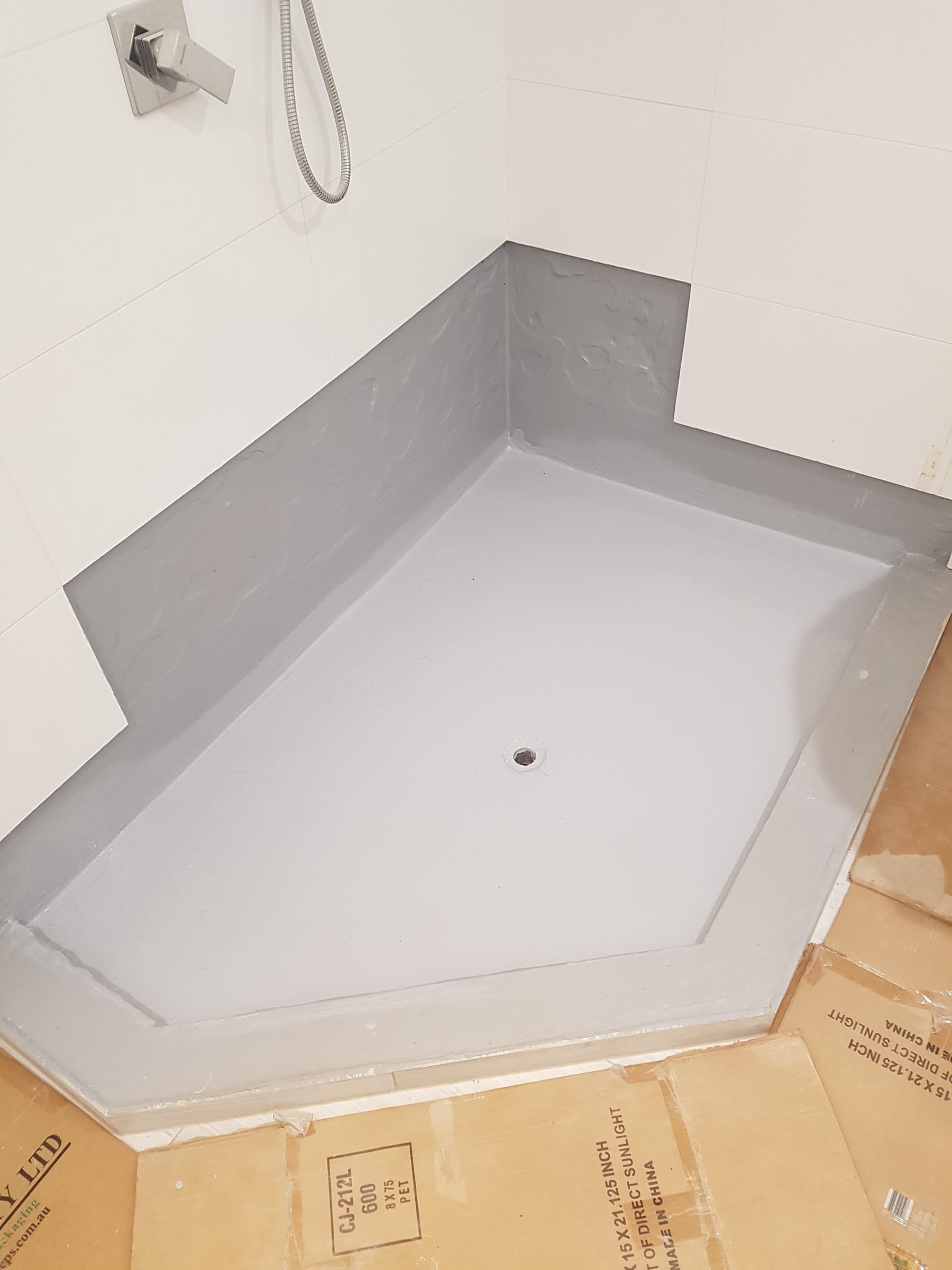 Shower base waterproofed with grey membrane before tiling